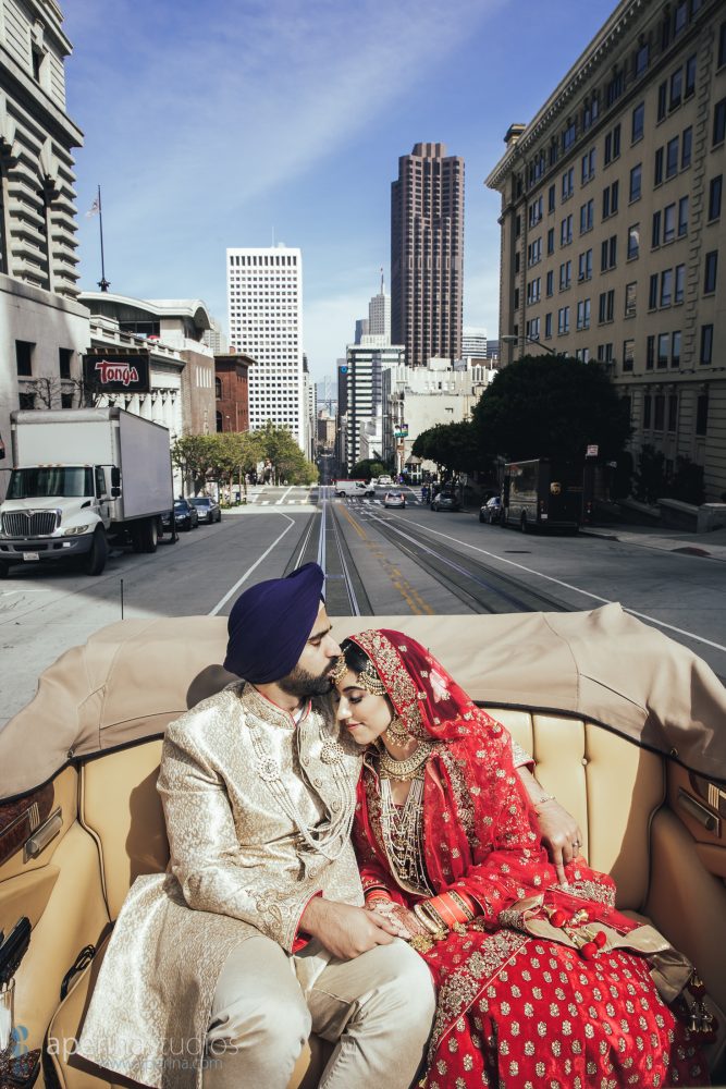 Indian wedding couple driving in antique car through the City of San Francisco