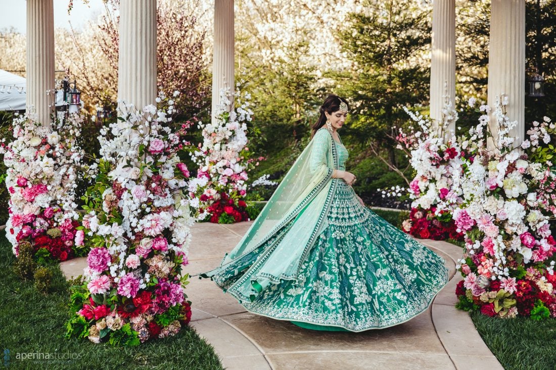 Indian Bride twirling while wearing stunning blue and green Anita Dongre lehenga on her Sangeet